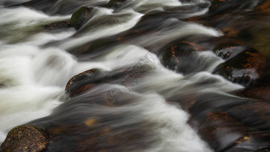 河流在岩石上流过而长期运动模糊不背景图片