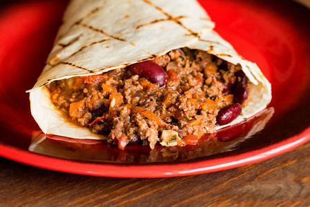 用红盘上的肉末特写新鲜烹制的墨西哥卷饼图片