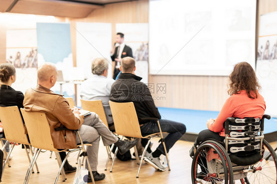 坐在轮椅上参加商务会议谈话的面目全非的女人的后视图商业和创业研讨会演讲者在商务会议上发表演讲会图片
