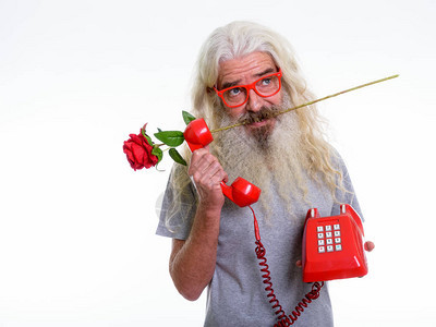 工作室拍摄的长胡子老人在拿着旧电话时思考和咬图片