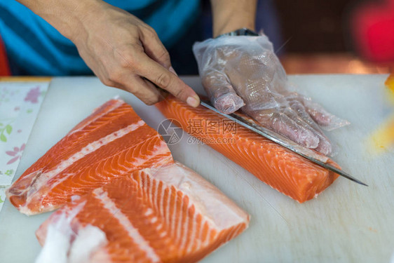 亚洲厨师在船上用刀切鲑鱼图片