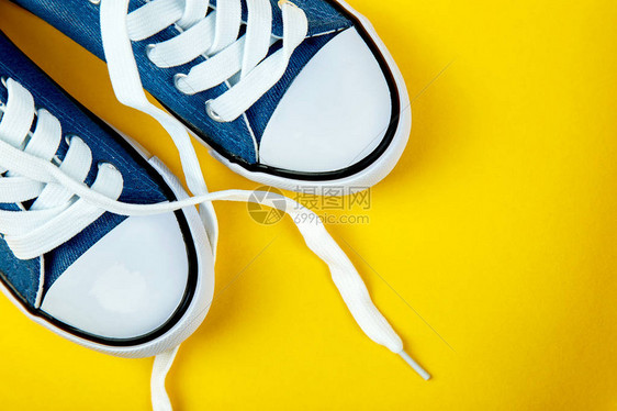 黄色纸背景上的蓝色女或男运动鞋平躺顶视图最小的背景时尚博客或杂志概念复制图片