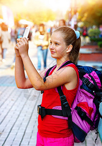 带着背包在智能手机上自拍的旅游女孩和城市文化展地露天步行街道图片