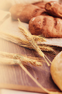 美味的新鲜烘焙产品和木制背景上的小麦穗新鲜出炉的面包产图片