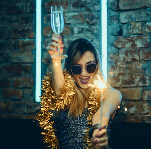 欢庆夜的年轻快乐女人与烟火共饮香槟夜总会女俱乐部员玩得开心图片