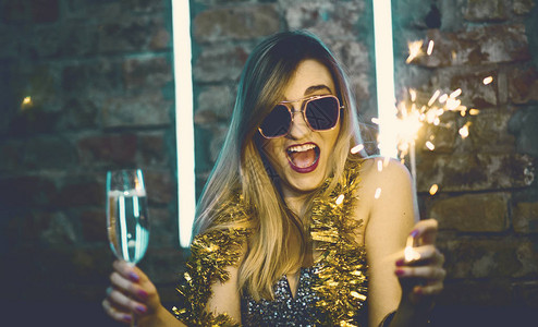 欢庆新年夜的年轻快乐女人与烟火共饮香槟夜总会女俱乐部员玩得开心图片