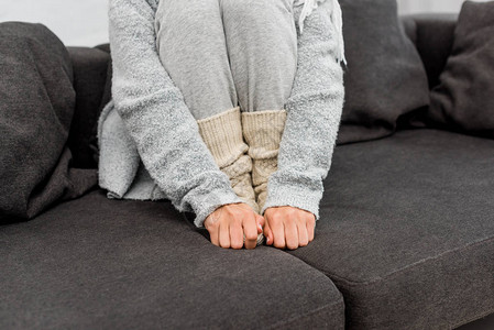 身着温暖衣服坐在沙发上和暖脚的冷图片素材