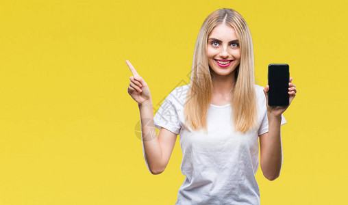 年轻美丽的金发美女在孤立的背景中显示智能手机非常快乐地用手和指图片