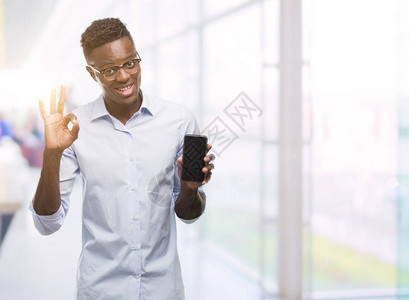 使用智能手机的非洲青年男子用手指签好标志图片