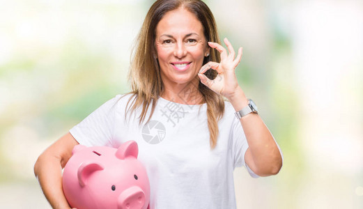 中年的黑皮女人利用小猪银行在孤立的背景里存钱用手指做好标记图片