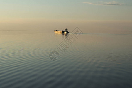 日落时湖上的金色船夕阳照亮了湖面上的驳船地平图片