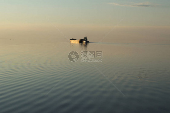 日落时湖上的金色船夕阳照亮了湖面上的驳船地平图片