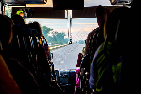公共汽车与乘客的轿车的光透过公共汽车的挡风玻璃从旅游巴士的车窗图片