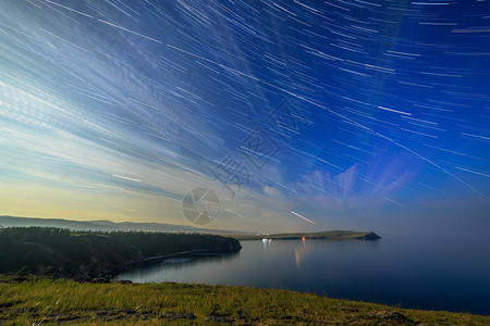 俄罗斯Baikal湖奥尔孔岛云和星在小海湾的月光之夜恒星的长轨图片