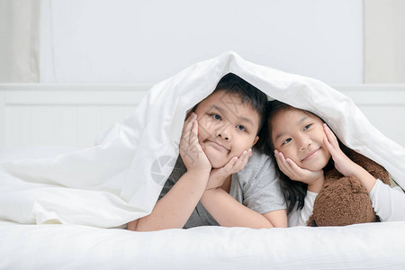 两个快乐的兄弟姐妹躺在毯子下的孩子快图片