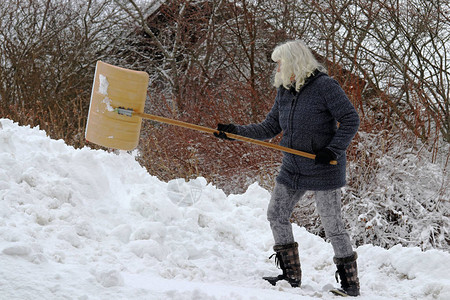 一个女人在冬天下铲雪在雪瀑图片