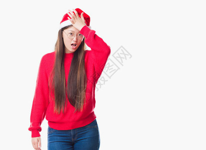 身穿圣诞帽的年轻女因错误而惊讶地用手捂着头图片