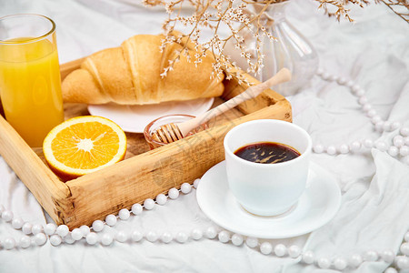 意式咖啡早上好白色床单上的欧陆式早餐一杯咖啡橙汁羊角面包木托盘上的果酱顶视图平躺复制空间背景