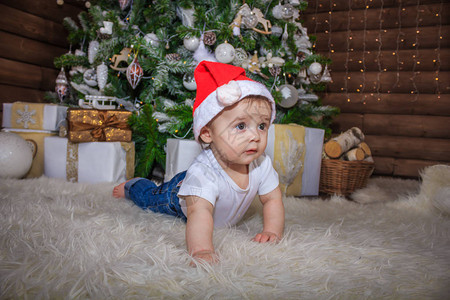 穿着精灵服装的婴儿在圣诞树下玩旧木火车和毛绒玩具熊图片
