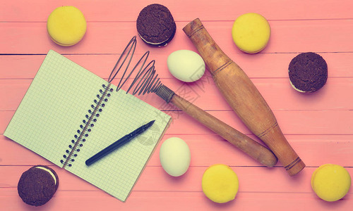 制作巧克力饼干马卡龙粉红木背景的成分鸡蛋滚动针卷轴配有笔的食谱笔记图片