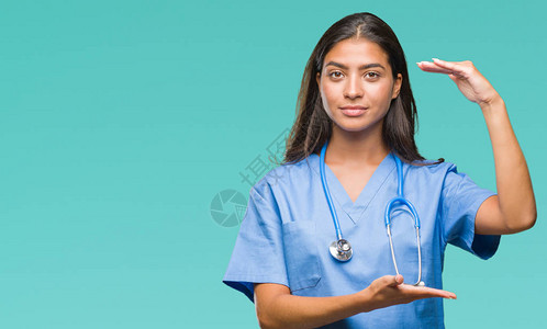 年轻的阿拉伯医生外科医生女人在孤立的背景下用双手展示大小的标志图片