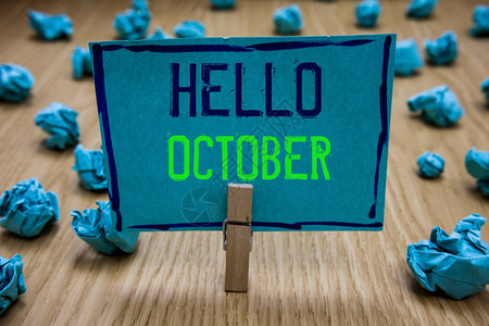 手写文字写你好十月概念含义上季度第十个月30天季节问候衣夹拿着蓝纸便条皱巴的纸图片
