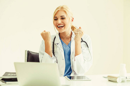 快乐的成功女医生在医院或医疗机构工作时在办公桌上写医疗报告时感到很愉快背景图片