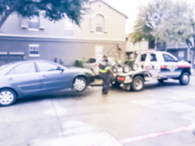 老式色调模糊损坏的汽车被卡车从公寓大楼拖到机械店图片