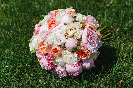 美丽的花束从盛开的牡丹和玫瑰的壮丽花朵躺在绿草特写婚礼当图片