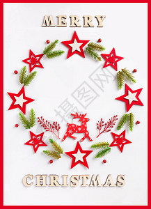 新年贺卡在白纸上刻有木制字母的圣诞快乐云杉与红星的节日花环带红框图片