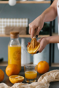 女人手挤新鲜橙汁的近景图片