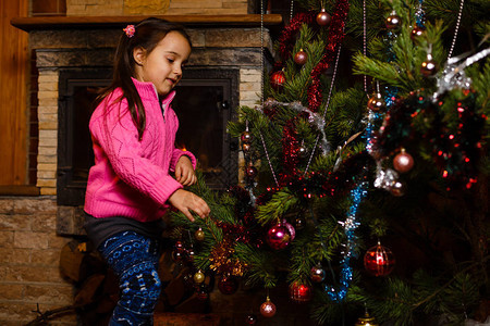 小女孩在圣诞树上装饰着灯光和糖果图片