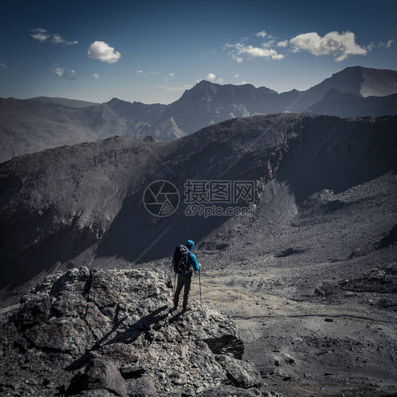 无法辨认的登山者的侧边景色背包站在悬崖上在阳光明媚的日子看图片