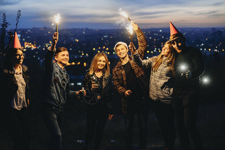 一群年轻朋友拿着啤酒和闪亮的火花图片