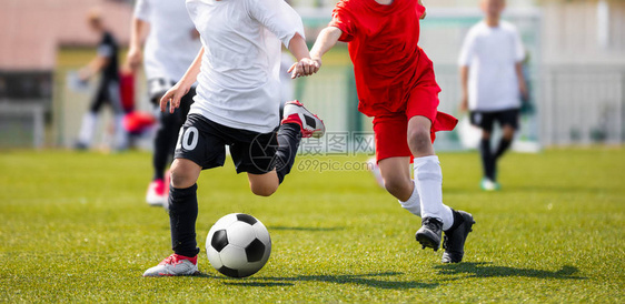 2名参加足球运动跑步和踢球比赛的年轻男孩图片