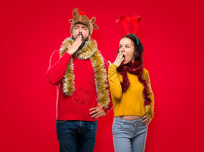 一对为圣诞节日打哈和亲手遮住嘴的夫妇图片