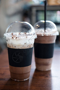 两块塑料拿掉咖啡杯冰咖啡摩卡和咖啡厅木桌上的巧克力图片