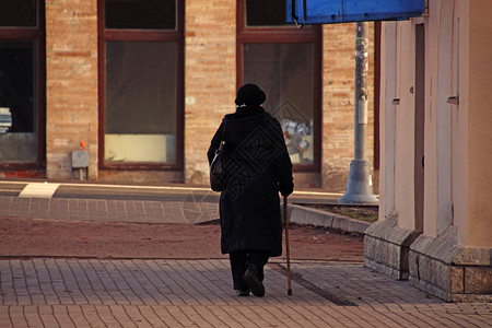 拄着拐杖走在街上的老妇人图片