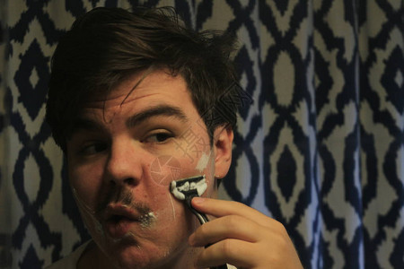 一名年轻人在浴室镜子前刮脸图片