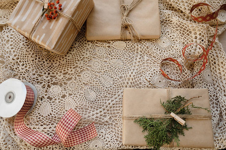 经典古圣诞礼品盒在花边桌布背景上赠送圣诞节礼物配手工装饰复制空图片