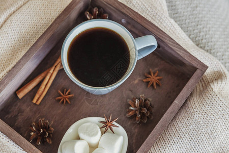 生锈木盘甜棉花糖和暖羊毛衫上的一杯咖啡杯图片