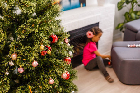 可爱的小女孩坐在壁炉和圣诞树附近的地板上图片