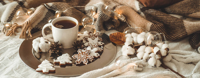 杯茶或咖啡冷杉树枝雪花形状的圣诞饼干舒适的针织毯棉花和舒适的花环图片