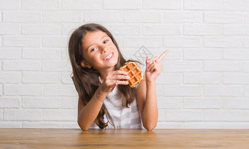 坐在桌子上吃华夫饼的年轻西班牙小孩图片