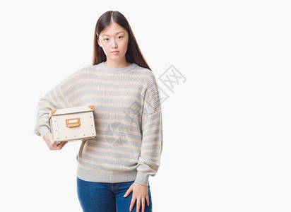 身陷孤立背景的中华女青年拿着一盒装满自信表情的盒子在图片