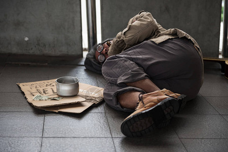 年老的病乞丐或无家可归的脏人睡在漫步道上图片