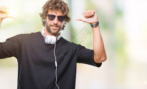 英俊的西班牙裔男子戴着耳机在与世隔绝的背景下听音乐图片