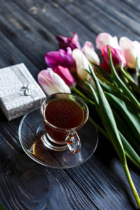 灰色木制桌边的彩色郁金香圆滑盒和咖啡杯情人节春天背景花岗岩图片