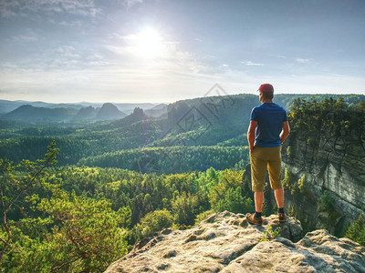 在一块石头上观察风景的人孤独的年轻运动员站在山图片