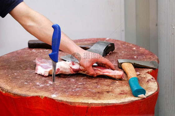 屠夫在农场市砍刀店的木制头上切肉用刀图片